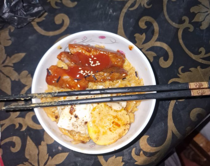 The image features a bowl of food, possibly containing noodles or rice with meat and sauce, accompanied by chopsticks resting on top. The dish appears to be well-prepared and visually appealing. The photo also includes text that reads "Eid vibes + good food + @bitgetBDT gains = perfect combo". This suggests that the image is related to a festive occasion or celebration, possibly during the Chinese New Year, where people often enjoy traditional dishes with family and friends.
