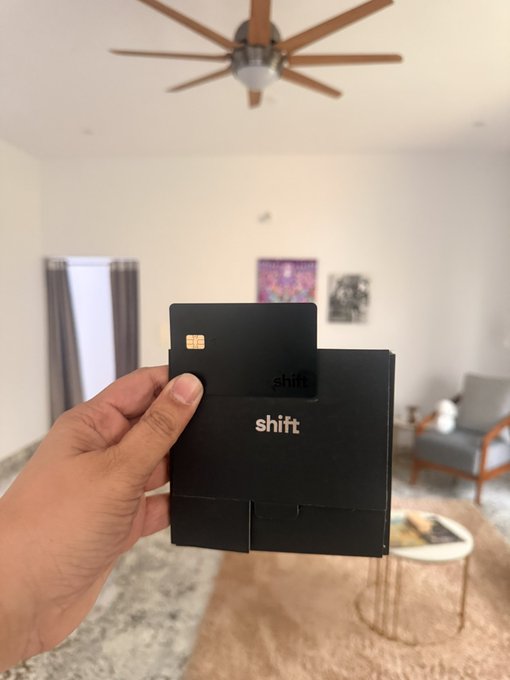 A hand holds up a sleek black "shift" card with an EMV chip in a modern living room, showcasing the new privacy-focused crypto wallet just delivered, matching the post's excitement about receiving their Shift card for ledgerless, private crypto transactions.