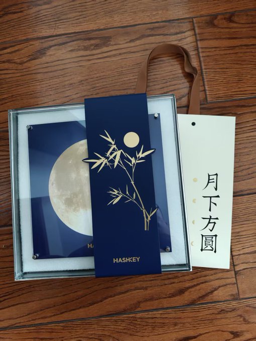 A gift set in a box with a brown ribbon, containing a blue decorative card featuring a moon and gold bamboo design with the brand name 'HASHKEY' and a tag with Chinese characters '月下方圆'.