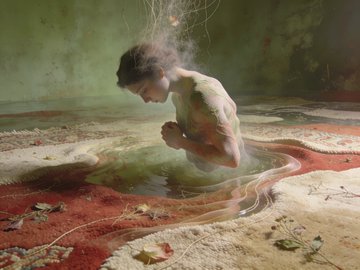 A surreal digital artwork depicting a pale young girl crouching inside a shallow pool of water on a textured red and tan floor, with strands of hair suspended in the air above her.