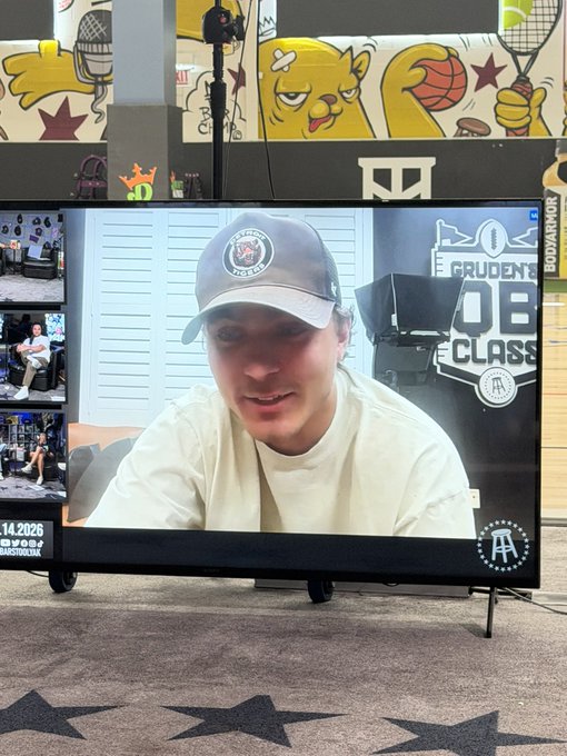 A man in a Houston Astros cap appears on a monitor during what looks like a Barstool Sports live stream, with the text "GRUDEN'S QB CLASS" visible on a backdrop. The setup, including the Barstool "B" stool logo and "Barstoolbook" branding, suggests this is a recording of a sports talk show or podcast broadcast.