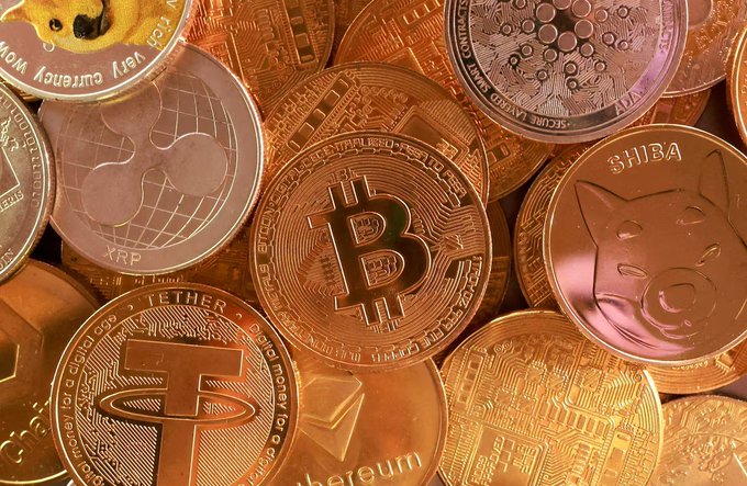 A collection of physical cryptocurrency coins including Bitcoin, XRP, Tether, Ethereum, and Shiba Inu coins displayed together.