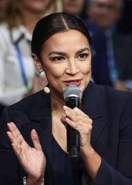 Alexandria Ocasio-Cortez (AOC) speaks into a microphone while gesturing with her hand, captured mid-address at what appears to be a public event. The image accompanies news that she has overtaken Senator Marco Rubio in 2028 presidential odds, securing a 13% chance of winning the White House.
