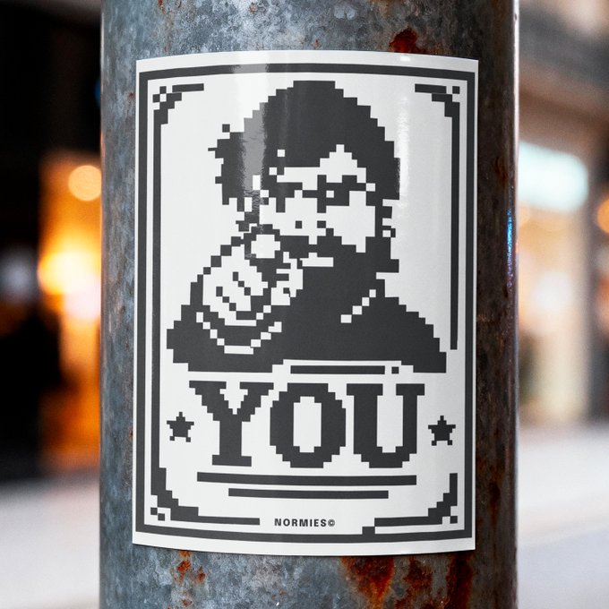 A black and white pixel art sticker on a metal pole depicting a hooded figure holding an ice cream cone with the word 'YOU' below and 'NORMIES©' at the bottom.