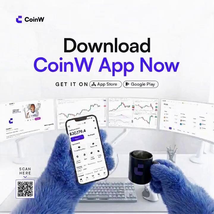 The image shows a person holding up their phone, which has an app for CoinW displayed on its screen. They are also holding a coffee cup and a keyboard, possibly indicating that they are working or browsing while enjoying a hot beverage. The background of the image is white with a monitor displaying stock market data.