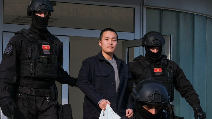 The image shows a group of police officers standing next to each other, with three of them wearing black helmets and body armor. One of the men has his hand over his head while holding a white bag or paper. The scene appears to be set in front of a building, possibly an office or a public place. The post about crypto seems unrelated to this image, as it does not provide any context or information that would help explain why these police officers are standing together and what the content of their conversation might be related to.