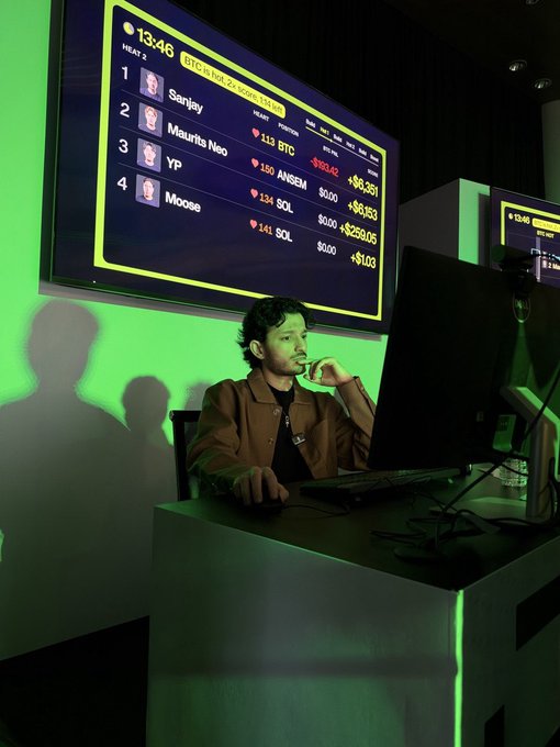 A focused trader competes at a live trading event hosted by @joinfrontier, with a leaderboard showing the BTC market heats (Heat 2) where YP leads with $8,561 over Sanjay, Maurits Neo, and Moose, all trading Bitcoin against various fiat and crypto pairs. The dramatic green-lit arena captures the intensity of the competition being praised in the post.