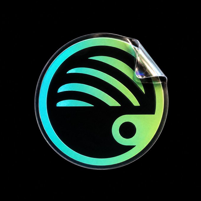 A holographic Spotify logo sticker is shown against a black background. The sticker is partially peeled back, revealing a shimmering iridescent layer.