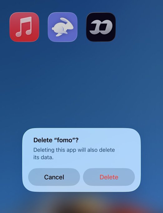 An iOS screen showing a confirmation dialog that reads "Delete \"fomo\"? Deleting this app will also delete its data." with Cancel and Delete buttons, above app icons including Music and Apple Shortcuts.