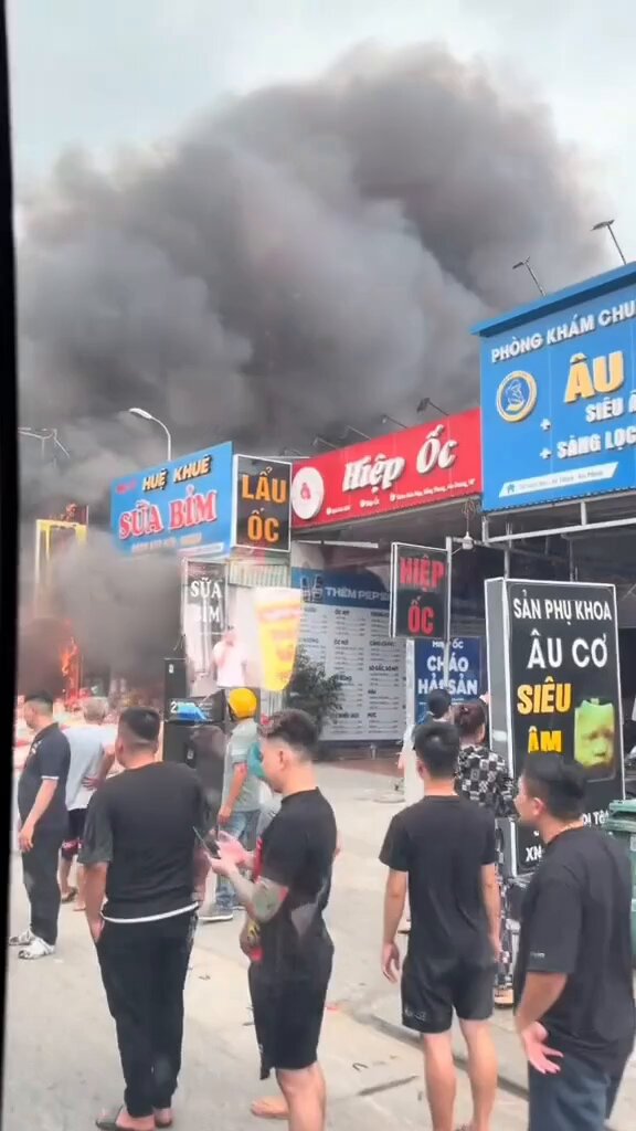 The image shows a group of people standing outside a building with smoke coming out of it. The crowd appears to be gathered around an entrance, possibly witnessing an event or emergency situation. There are several individuals visible in the scene, some closer to the front while others are further back. A person is holding a cell phone and seems to be capturing the moment.

The post includes text that reads: "Is your crypto wallet about to be hacked by Quantum ? @quipnetwork is here: - Protect your post-quantum wallet today - Mine using Quantum ... farm early or regret it after Q-Day." This message appears to be related to a recent event, possibly involving the burning building and its impact on people's digital assets.
