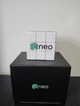 A white Rubik's cube with 'neo' printed in green and black sits atop a black box also branded with the 'neo' logo.
