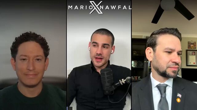 The image shows three men sitting next to each other, with one man wearing a suit and tie while another has short hair. The third man appears to be balding. They are all smiling at the camera during an interview or discussion on a topic related to cryptocurrency.