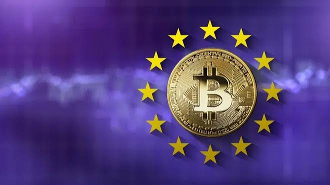 A Bitcoin token sits against a blurred backdrop of the European Union flag's circle of yellow stars, symbolizing the intersection of cryptocurrency and EU regulation as Binance withdraws its MiCA license application ahead of the July 1 deadline.