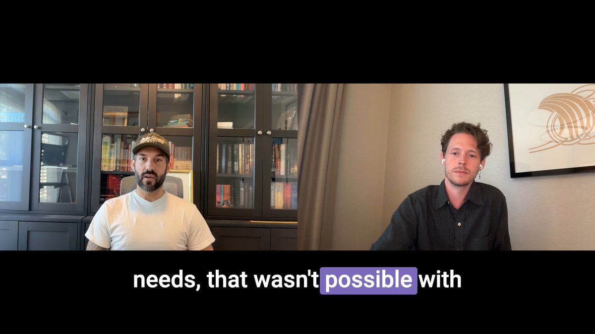 A split-screen video call showing two men, one wearing a white cap and t-shirt in front of a bookshelf, the other in a dark shirt; subtitles read 'needs, that wasn't possible with'.