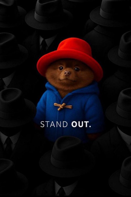 The image features a poster with a cartoon bear wearing a blue jacket, red hat, and tie, standing out against a black background. The text "Stand Out" is written above the bear's head, and there are several other hats scattered around the poster as well. The overall theme of the poster seems to be related to humor or entertainment, possibly featuring a character from a movie or TV show with a distinctive appearance.