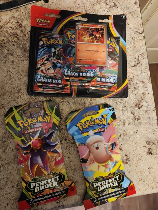 The image shows a collection of Pokemon trading cards scattered across a table, with two distinct sets of cards displayed side by side. The top set features a Pokemon card labeled "Chaos Rising" and another one labeled "Chaos Order", while the bottom set has a Pokemon card labeled "Pikachu". These cards are likely part of a larger collection or assortment that someone is organizing or sorting through, possibly for trading purposes with friends who share an interest in Pokemon.