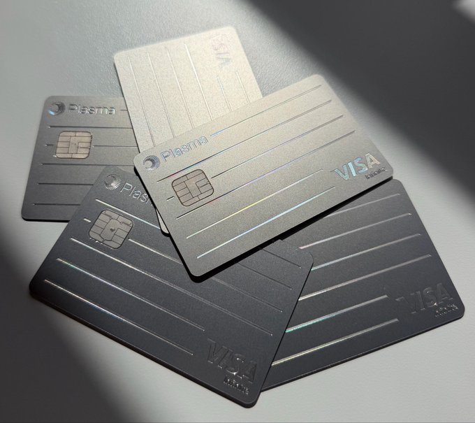 A scattered arrangement of metallic gray and silver Visa credit cards branded with "Plasma" on a sunlit surface, visually representing the 700+ platinum sign-ups milestone for the Plasma One launch.