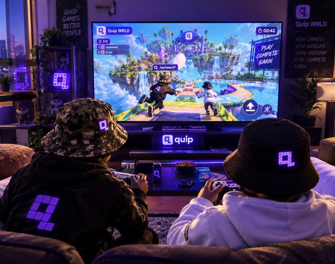 Two people wearing camo and black Quip bucket hats play a colorful platformer video game on a large TV displaying the "Quip WRLD" logo and a "PLAY COMPLETE EARN" banner.