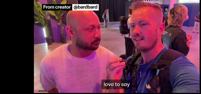 Two men speak into a handheld microphone at an expo-like event with colored lighting. On-screen text reads “From creator @bardbard” at the top and “love to say” near the bottom.