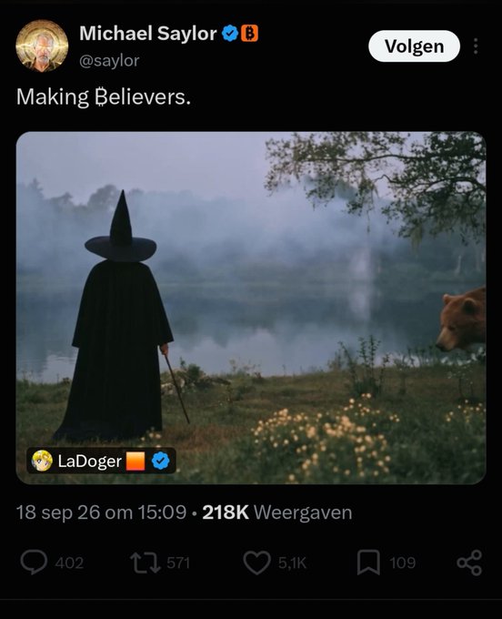 The image shows a tweet from Michael Saylor (@saylor) captioned "Making Believers," featuring a mystical scene of a cloaked witch-like figure in a pointed hat by a misty lake, with a bear partially visible on the right. A community label reads "LaDoger" and the post has 5.1K likes, 571 reposts, and 402 replies. The accompanying caption "Saylor understands wizz season" humorously connects the wizard imagery to crypto market speculation, with the lurking bear symbolizing bearish market forces.