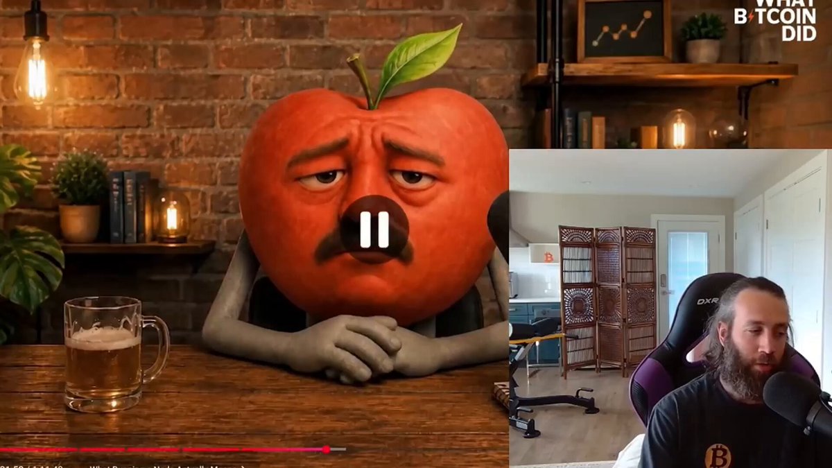 The image features a cartoon apple sitting at a table with a beer mug next to it, accompanied by a man wearing a beard who appears to be talking into a microphone. The scene takes place in front of a brick wall, suggesting an indoor setting like a bar or a pub.