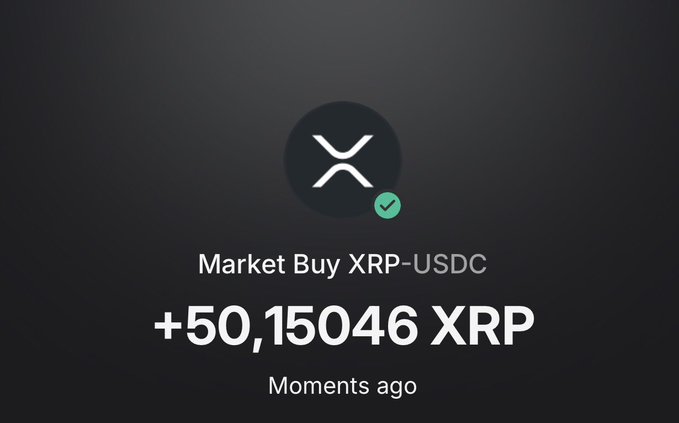 A digital notification screen on a dark background showing a successful market buy of '+50,15046 XRP' for XRP-USDC from moments ago, featuring the XRP logo.