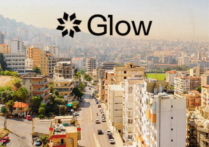 The "Glow" logo is overlaid on an aerial view of a sun-drenched Lebanese city with sprawling urban buildings and distant hills. The image visually reinforces the post's theme of Lebanon's abundant sunshine, setting the scene for how Glow's solar farms are harnessing 300 days of yearly sunlight to combat the country's limited grid power.
