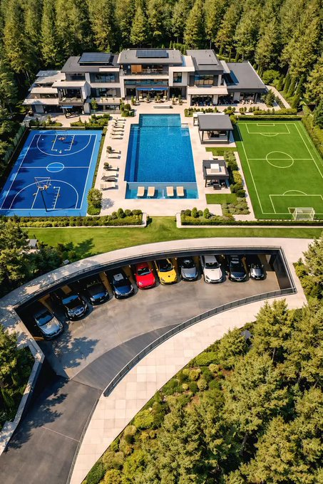 An aerial view showcases an expansive luxury estate featuring a modern mansion, large swimming pool, private basketball and soccer fields, and a curved garage housing an impressive collection of sports cars. The image humorously represents the lavish lifestyle the poster envisions after unstaking $LOAN tokens on the Metal Blockchain between 2029 and 2031.