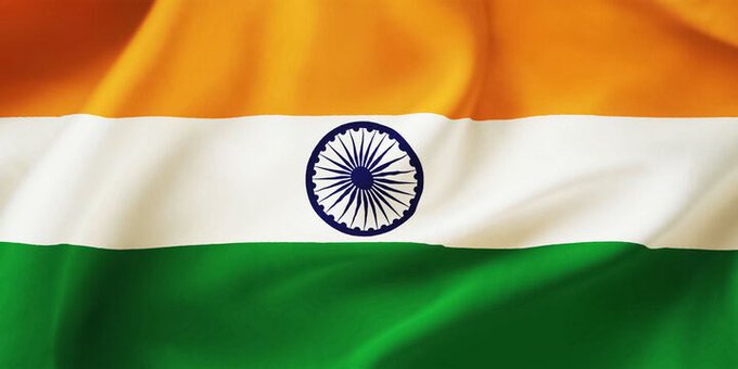 The image shows the waving national flag of India, featuring its tricolor design of saffron, white, and green horizontal stripes with the navy blue Ashoka Chakra wheel in the center. The flag visually represents the Indian market context of the post, which highlights a stablecoin supply crunch in India where $USDT is trading at a significant 8.5%+ premium over the official USD/INR exchange rate.