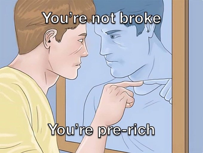 A young man points at his reflection in a mirror, accompanied by the meme text "You're not broke / You're pre-rich," reinforcing the post's motivational message that financial struggle is simply a phase before future success.