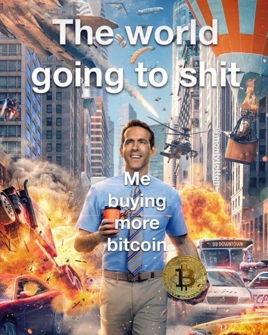 A meme featuring Ryan Reynolds smiling while holding coffee and a Bitcoin, set against a chaotic city destruction background with text 'The world going to shit' and 'Me buying more bitcoin', watermarked @mightydegen