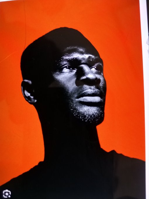 A bold poster features a black-and-white close-up of a man against a vibrant orange background, fitting the $AFRICA Solana meme coin's promotional post. The striking imagery, paired with the project's ticker and contract address, reinforces the meme coin's powerful branding and marketing push.