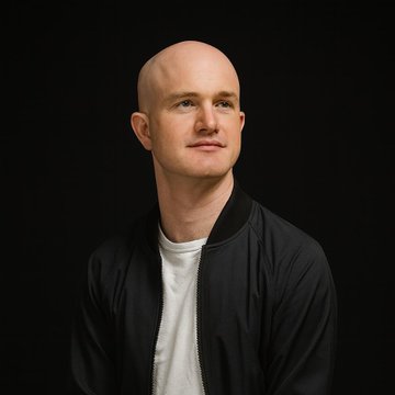 A studio portrait shows a bald man in a black bomber jacket over a white t-shirt against a solid black background.