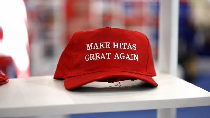 A red baseball cap displaying "MAKE HITAS GREAT AGAIN" sits on a white table, echoing the streamer's optimism in their day 12 stream as they push through crypto losses on kick.com/hitasyurek.