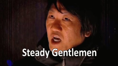 In the image, there's a man wearing a black jacket who appears to be talking or making a statement. The text "Steady Gentlemen" is written above his head, which seems to be related to the content of the image. The background features a dark color that contrasts with the man and the text, drawing attention to him.