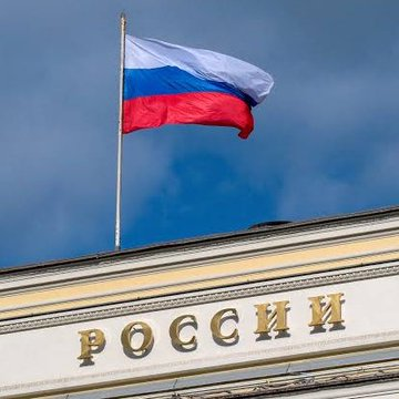 The Russian tricolor flag flies above a building inscribed with "РОССИИ" (Russia), symbolizing the country's official endorsement of new crypto trading regulations set to launch on Moscow Exchange and SPB Exchange starting September 1.