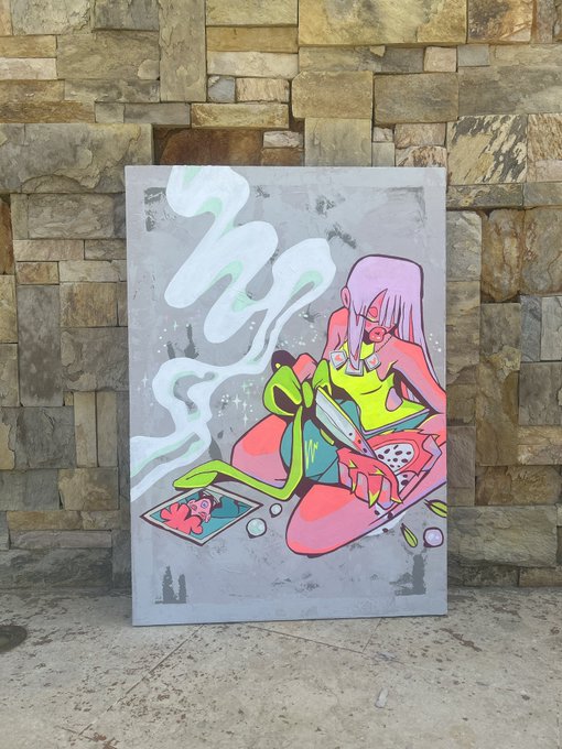 A colorful painting featuring a figure with pink hair and a green frog character, displayed against a textured stone wall on a concrete surface.