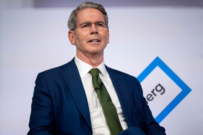A man with gray hair and glasses, wearing a navy suit and green tie, speaks on stage with a partial logo visible behind him reading "...erg." The image appears to relate to financial regulation, with the post referencing stablecoin issuers using short-term treasuries to support the debt market once related laws take effect.