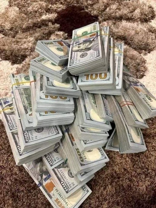 A large pile of banded stacks of US $100 bills arranged on a brown shaggy rug.
