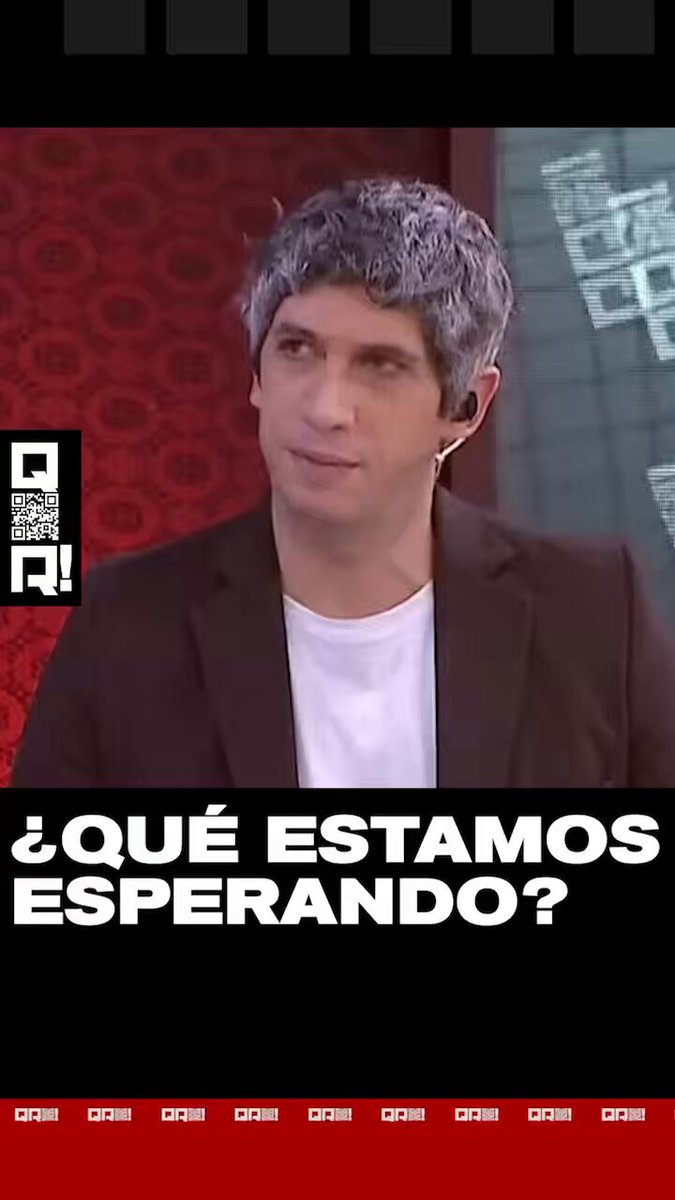 The image features a man wearing a black suit jacket with white lettering that says "que estamos esperando?". The man has gray hair and appears to be speaking into a microphone, suggesting he might be hosting or participating in an interview or discussion. The caption of the image reads "@Irihauser", which is likely a reference to the creator of the post. The focus on the man's appearance and his role in the creation process indicates that this could be a promotional piece for a project related to Milei, such as a podcast or video series featuring him.