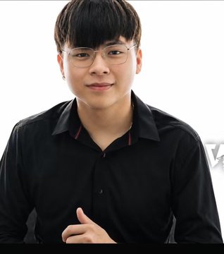A young man wearing glasses and a black button-up shirt smiles softly at the camera against a white background.