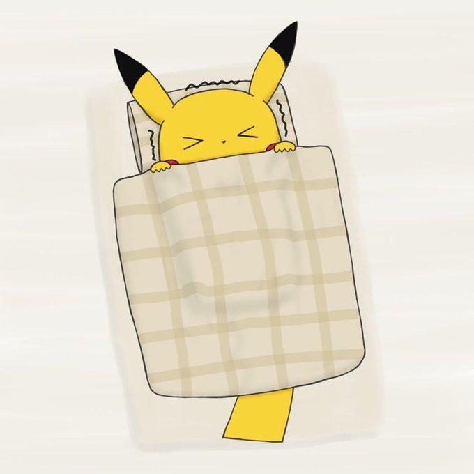 A plush toy of Pikachu tucked into a plaid blanket lies on a white surface, appearing to be asleep.