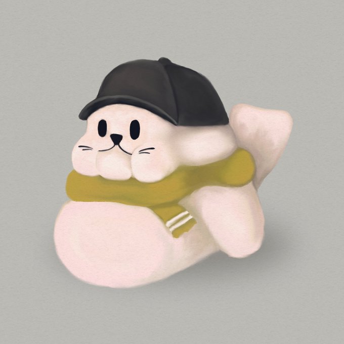 A small, stylized figurine of a white cat-like character wearing a black cap and an olive green scarf.