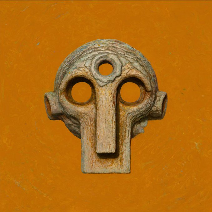A weathered, stylized stone skull-like mask with hollow circular eyes and a central nose hole is displayed against a textured orange background.