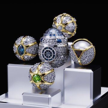 An ornate Fabergé-style egg with intricate diamond patterns and a clock face, surrounded by four jeweled egg-shaped objects featuring blue topaz, white pearl, and green emerald gemstones.