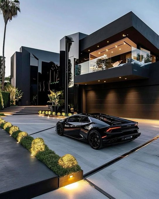 A luxury modern black house at dusk with a sleek black Lamborghini sports car parked in the driveway, illuminated by landscape lighting and featuring glass balcony railings.