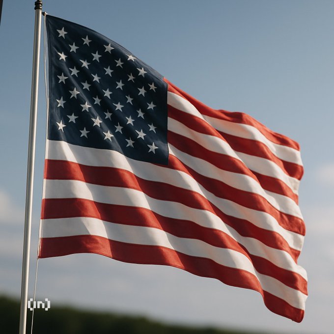 An American flag waves against a clear blue sky, mounted on a silver flagpole with a small '[in]' logo in the bottom left corner.