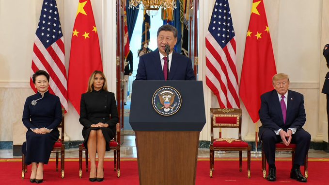 President Xi Jinping speaks at a podium flanked by the US and Chinese flags, with President Trump and others seated nearby, reflecting his statement on managing AI.