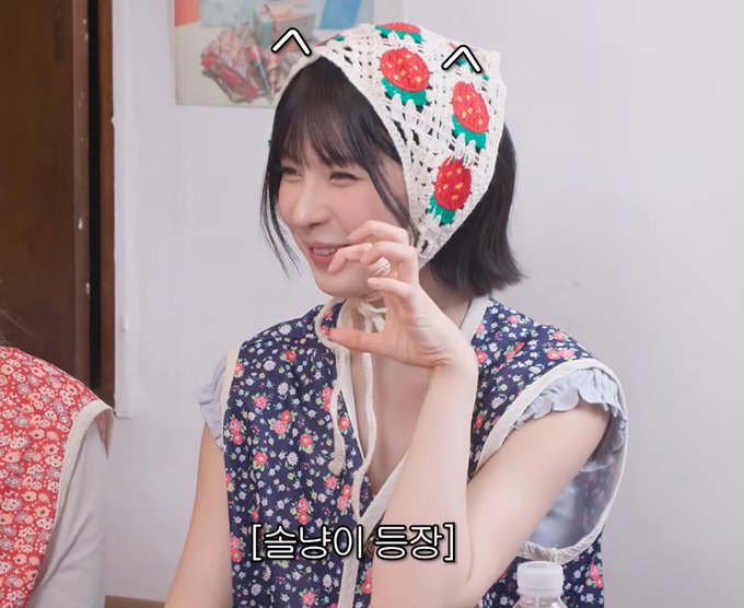 A smiling woman wearing a strawberry-patterned bonnet and a dark floral dress, with a cartoon cat face filter and cat ears added digitally; Korean text '[솔냥이 등장]' appears at the bottom.