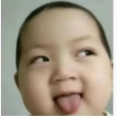 A close-up photo of a smiling baby with its tongue sticking out.